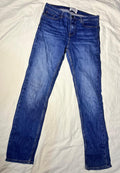 A pair of medium-wash blue denim jeans laid flat on a white fabric surface.