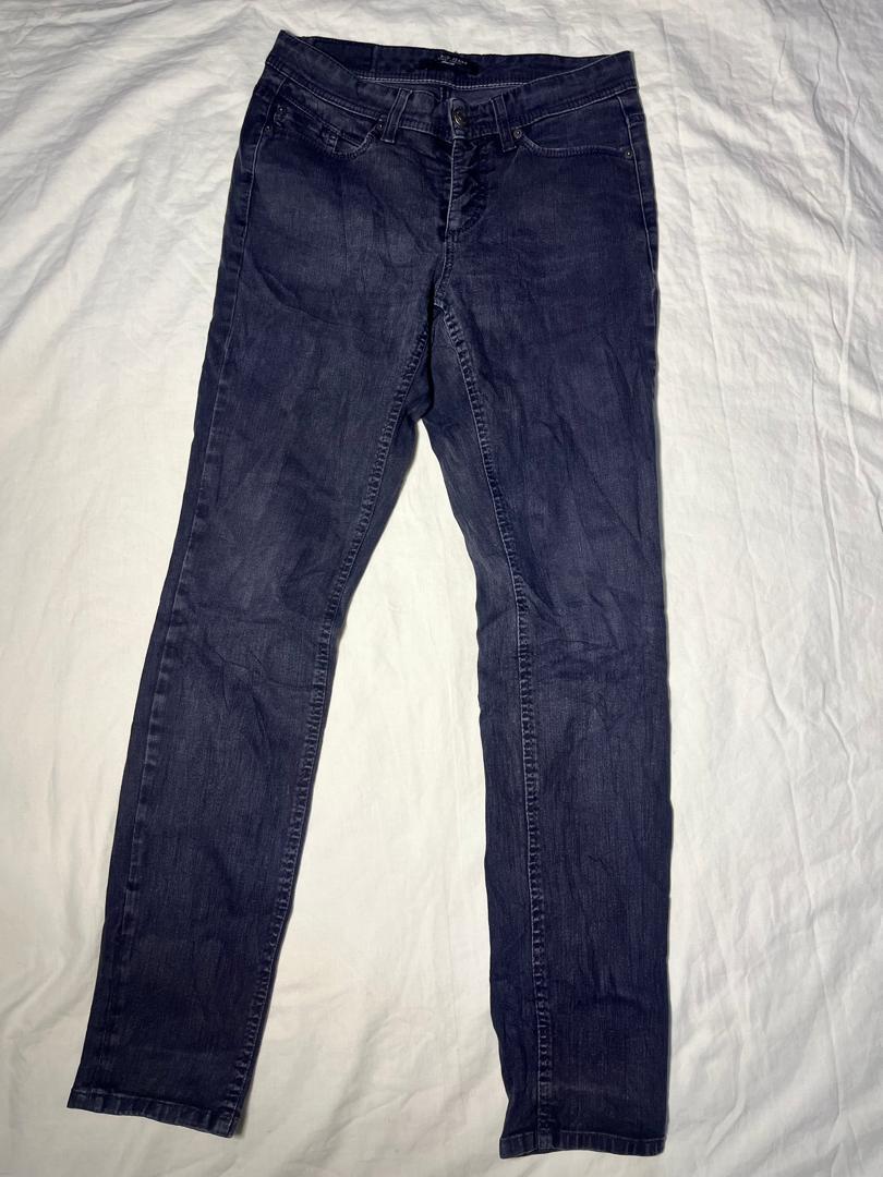 A pair of dark blue slim-fit jeans laid flat on a wrinkled white sheet.