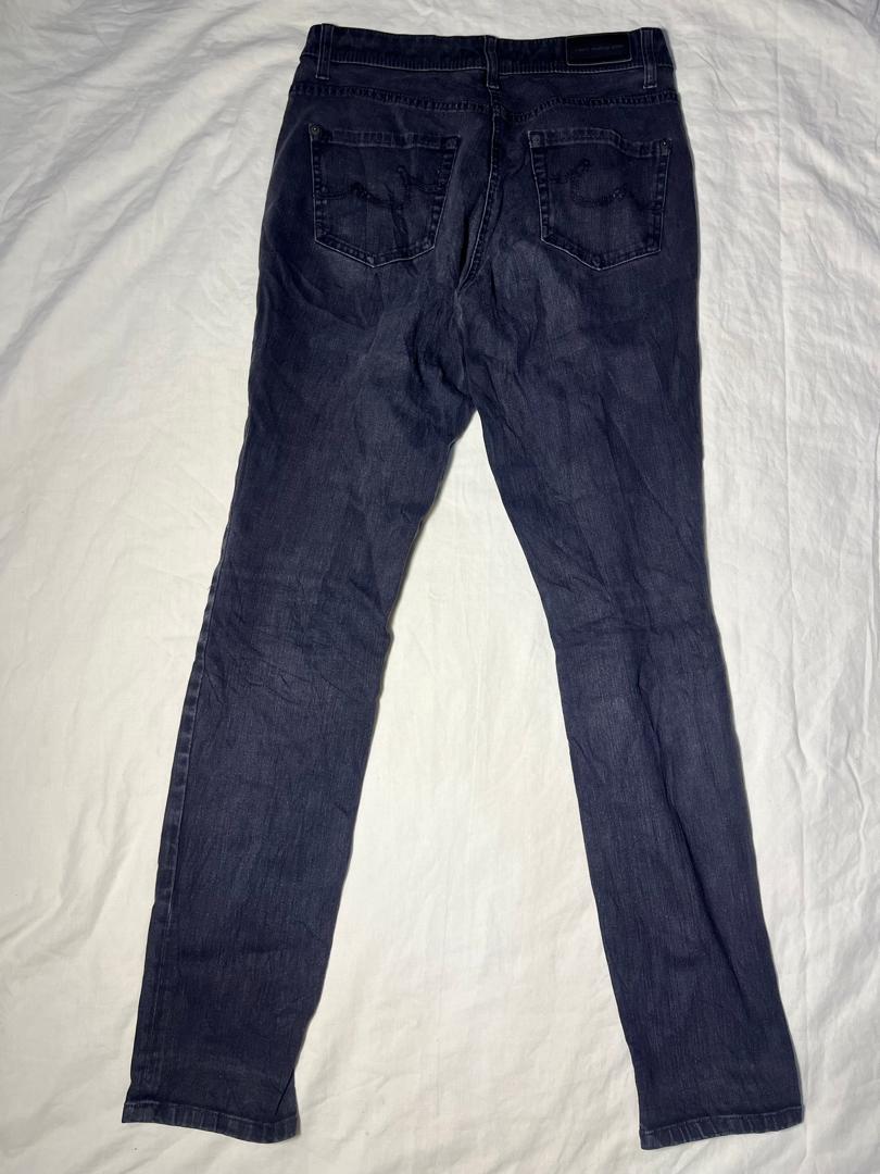 Dark blue denim jeans shown from the back, laid flat on a white fabric background.