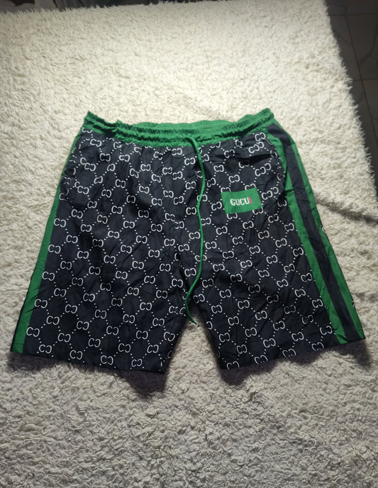 Gucci GG Supreme shorts in navy blue with green trim and white GG monogram pattern, laid flat on a white shag rug.