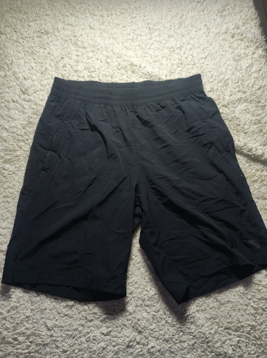 Black athletic shorts with an elastic waistband, laid flat on a white shag carpet.