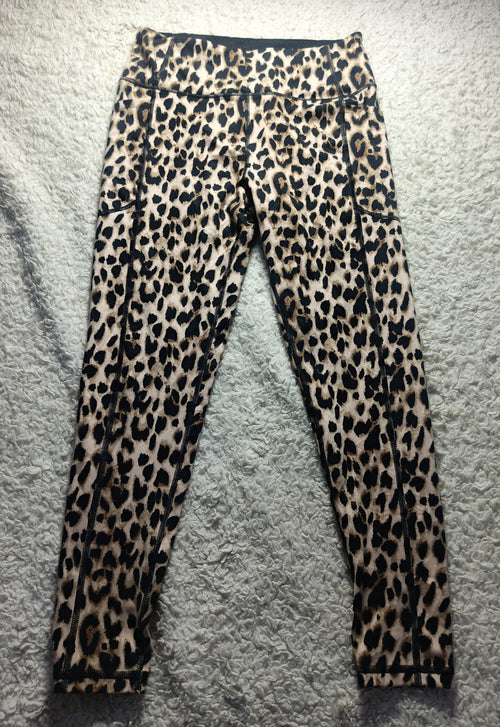 Leopard print leggings laid flat on a gray textured rug. The leggings feature a classic leopard pattern with black spots on a tan and brown base.