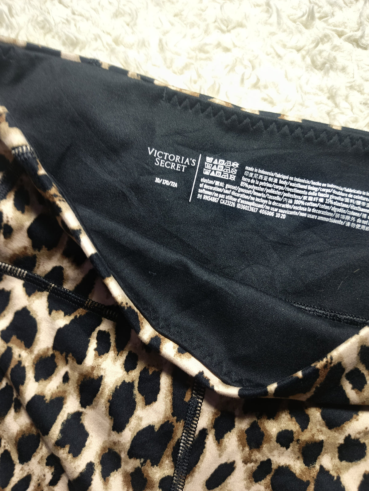 Close-up of a leopard print garment with a black inner lining and visible Victoria's Secret branding on the inside neck label.