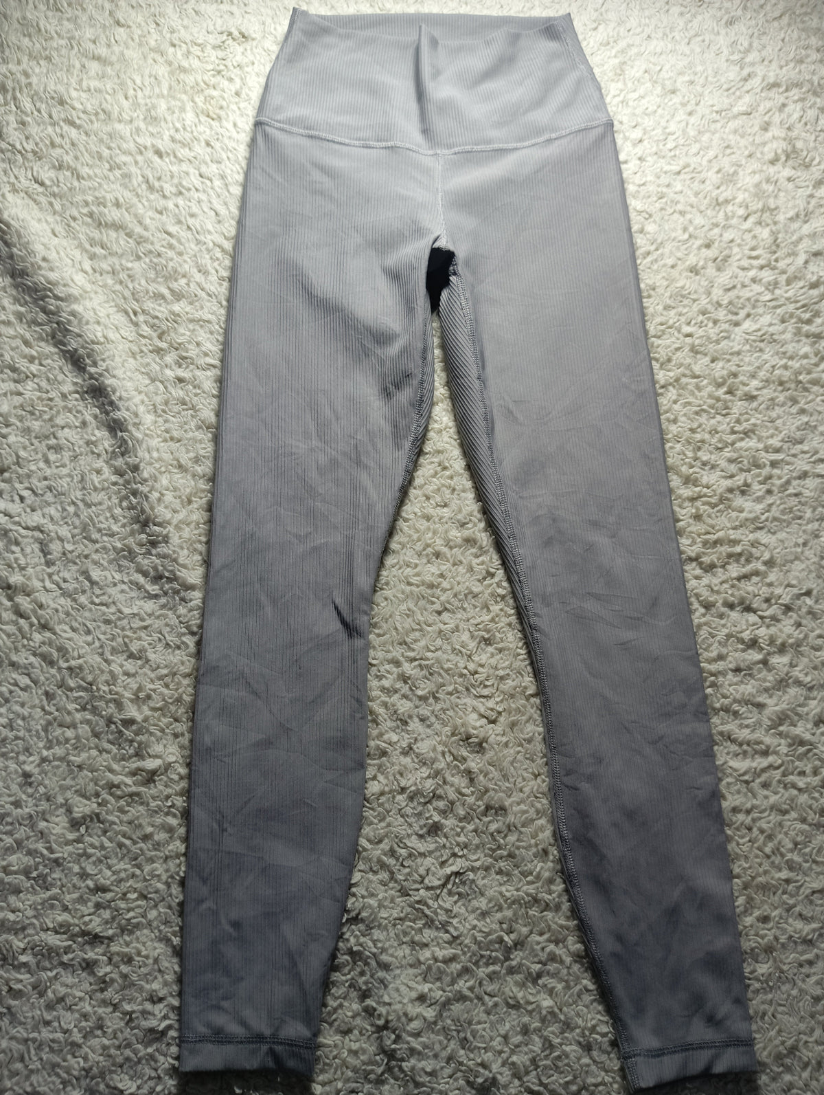 A pair of high-waisted gray leggings laid flat on a textured gray carpet. The photo is taken from above, with camera settings and text overlays visible at the bottom.