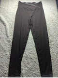 A pair of dark brown high-waisted leggings laid flat on a textured gray carpet. The leggings feature a crossover waistband with white contrast stitching and a small white embroidered detail on the left hip.