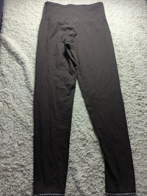 A pair of dark brown or very deep charcoal leggings laid flat on a textured gray carpet. The image has camera metadata text overlaid at the bottom.