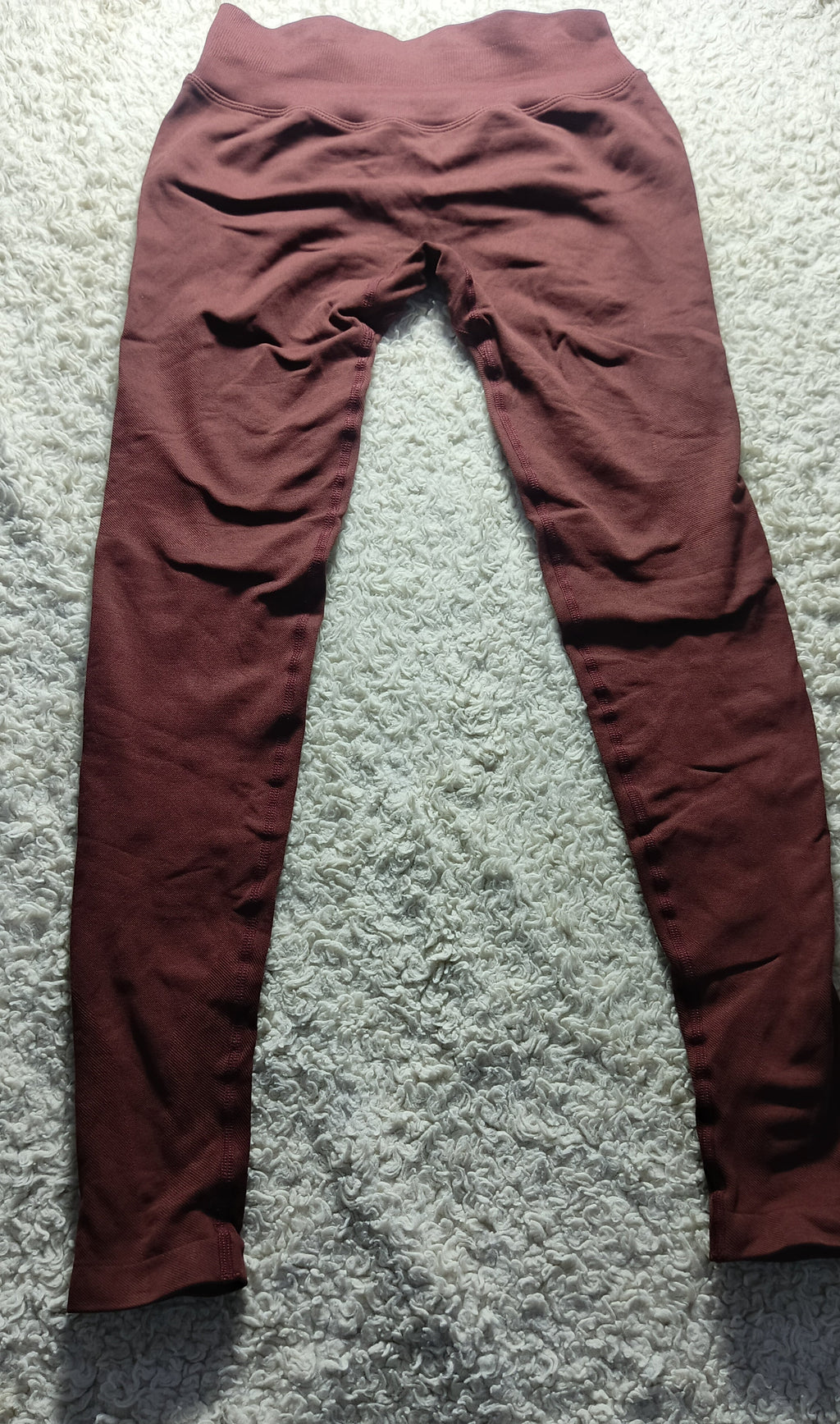 A pair of high-waisted, wide-leg leggings in a dusty rose or mauve color, laid flat on a textured gray carpet.