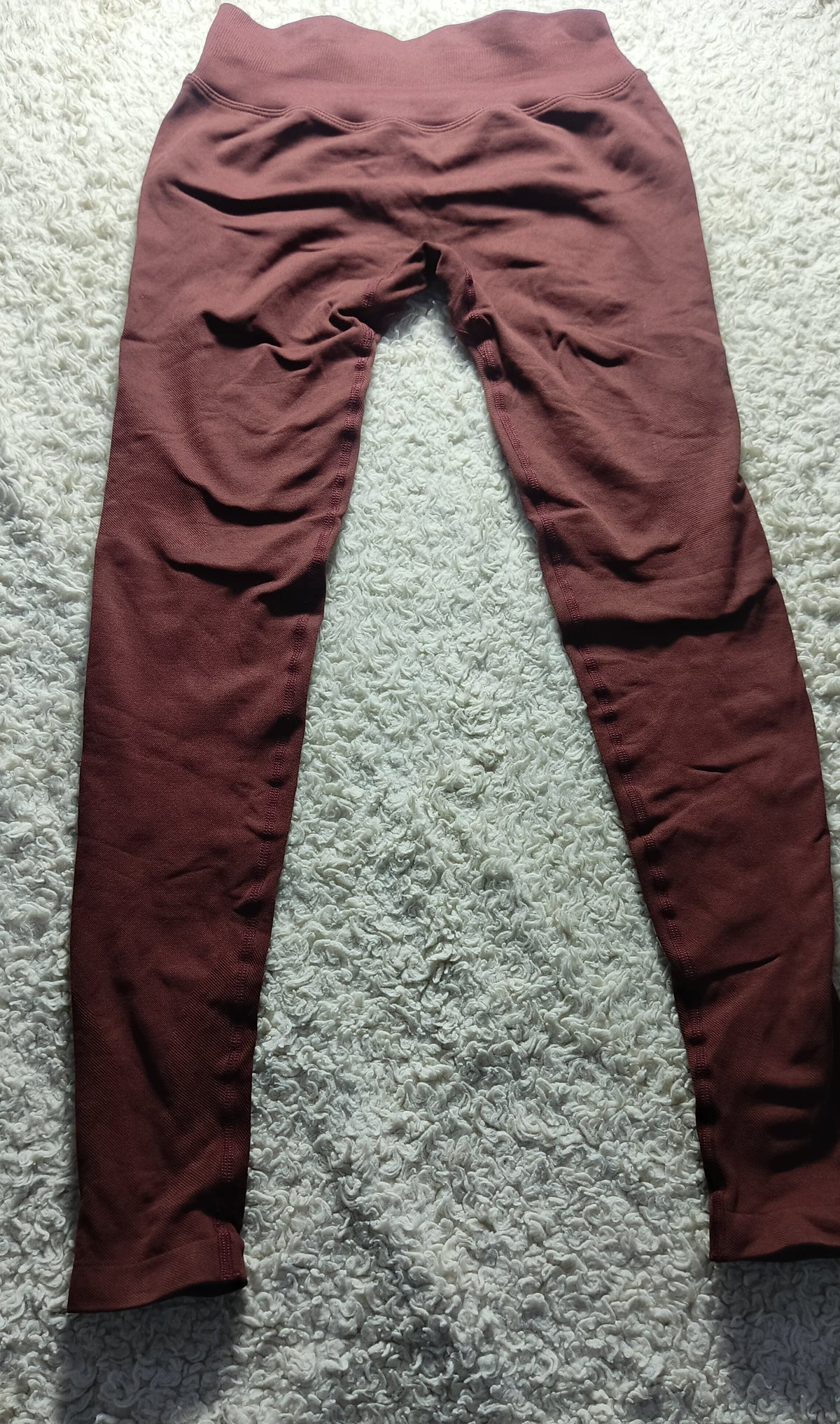 A pair of high-waisted, wide-leg leggings in a dusty rose or mauve color, laid flat on a textured gray carpet.
