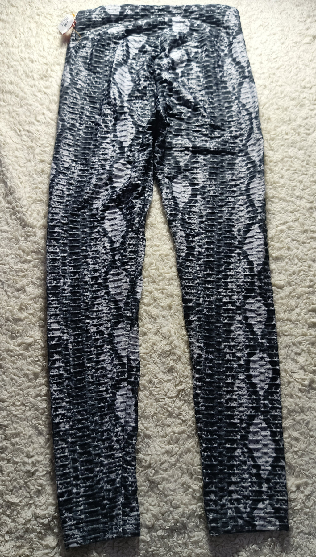 Black and white snakeskin print leggings laid flat on a beige carpet.