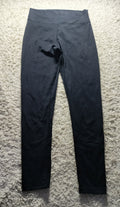 Black high-waisted leggings laid flat on a textured gray shag rug.
