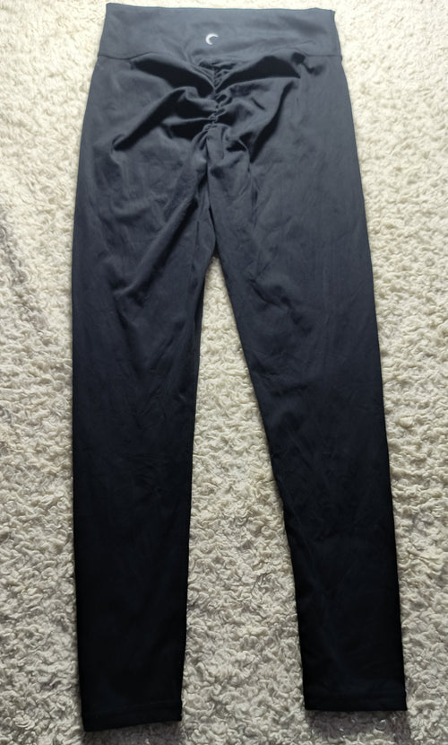 Black high-waisted leggings with a drawstring waist, laid flat on a textured gray carpet.