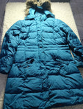 A teal blue puffer jacket with a fur-trimmed hood, laid flat on a white textured rug.