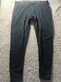 A pair of dark gray Nike Pro running tights laid flat on a textured gray carpet. The waistband features the white Nike Pro branding, and a small white Nike swoosh is visible near the lower left leg.
