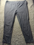 A pair of dark gray lounge pants or sweatpants laid flat on a textured beige carpet. The photo is taken from above with visible wrinkles in the fabric.