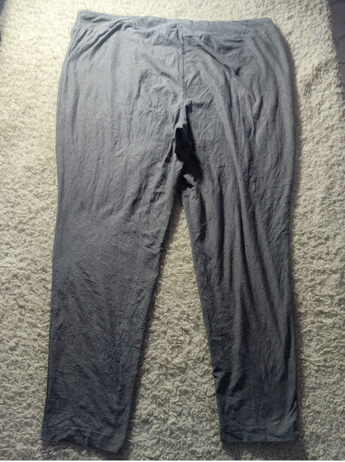 A pair of dark gray crinkled cotton pajama pants laid flat on a textured beige carpet.