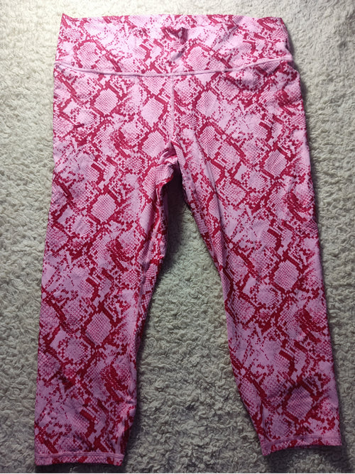 Pink and red snakeskin print leggings laid flat on a gray carpet background.