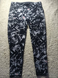 Black and white abstract patterned leggings laid flat on a beige carpet. The image has a camera watermark overlay at the bottom.