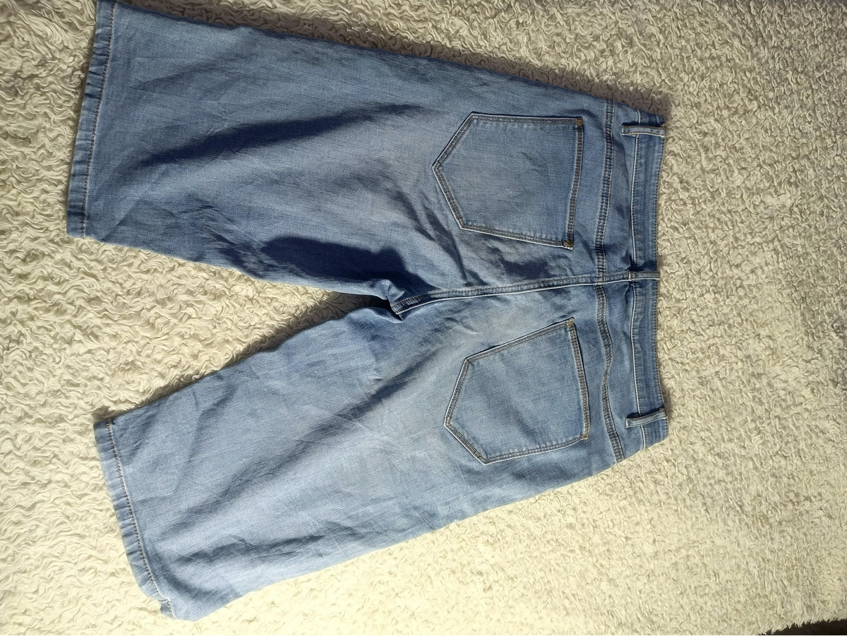 Light blue denim shorts laid flat on a beige carpet, showing the back pockets and waistband.