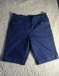A pair of dark blue denim shorts laid flat on a textured gray carpet.