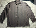 A long-sleeve button-up shirt with vertical brown and gray stripes, laid flat on a white textured rug.