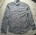 A gray long-sleeve button-down shirt with a subtle textured pattern, laid flat on a white shag rug. The brand label on the collar reads 'BONSAI'.