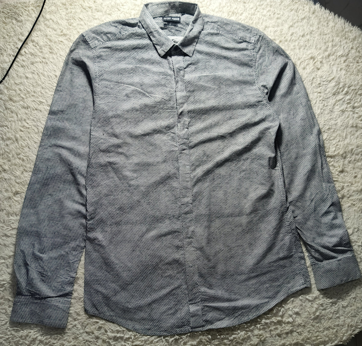 A gray long-sleeve button-down shirt with a subtle textured pattern, laid flat on a white shag rug. The brand label on the collar reads 'BONSAI'.
