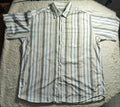A short-sleeve button-up shirt with vertical stripes in white, blue, and green, laid flat on a white textured blanket.