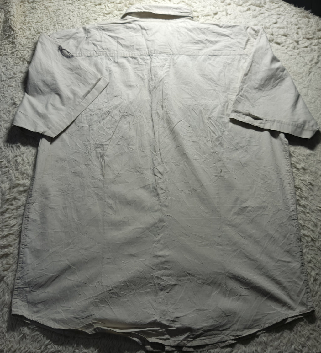 A light gray short-sleeve button-up shirt laid flat on a white shag rug, photographed from above.