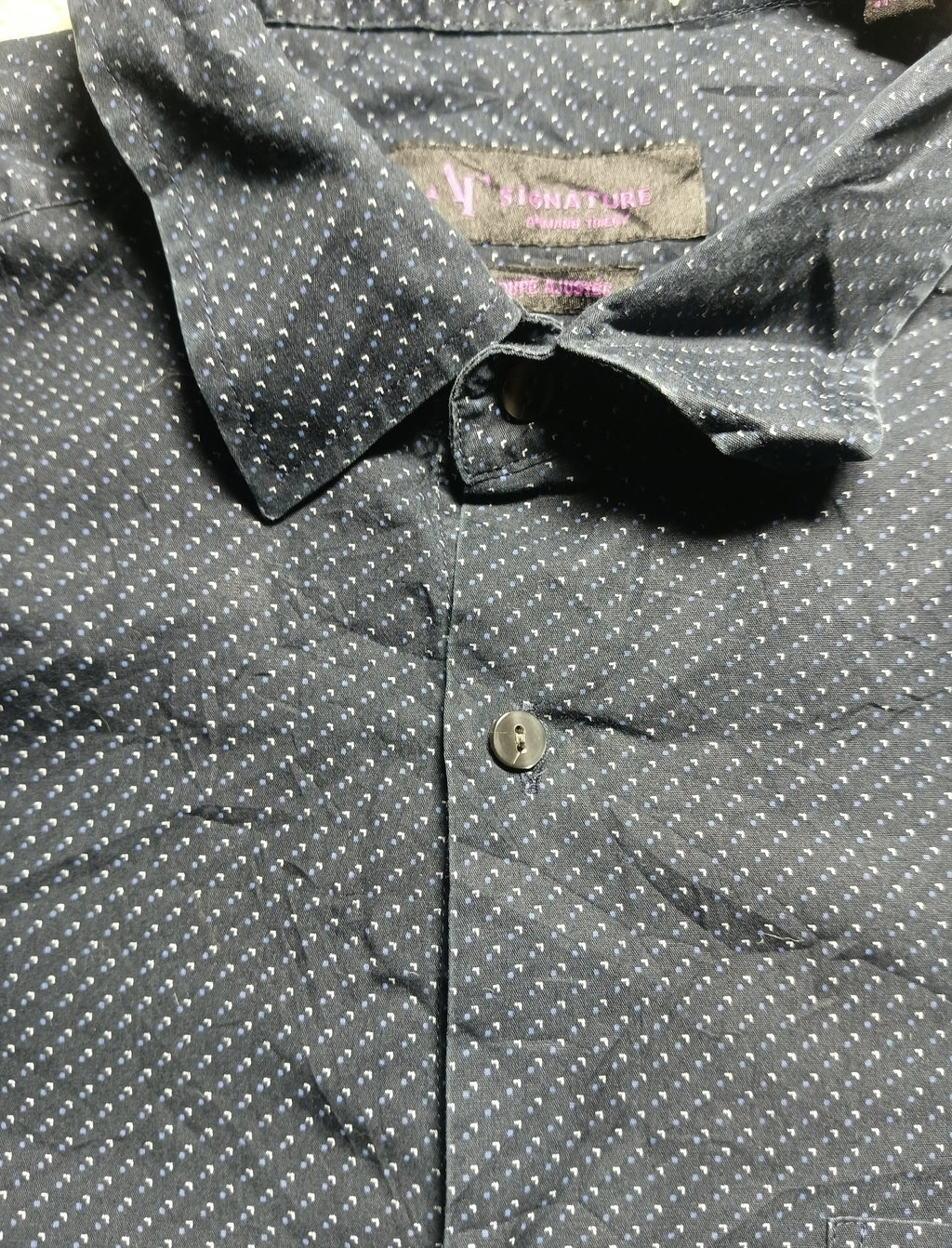Close-up of a dark gray button-down shirt with a small white geometric pattern, featuring a pointed collar and a single visible button.
