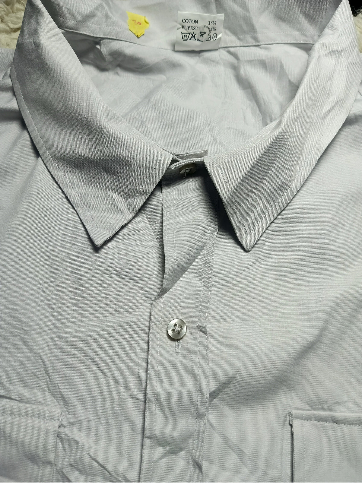 A light gray or silver-gray long-sleeve button-down shirt, shown in a close-up view with the collar and front button visible. The fabric has a slightly crinkled texture, and there is a visible inner neck label and a camera watermark at the bottom.