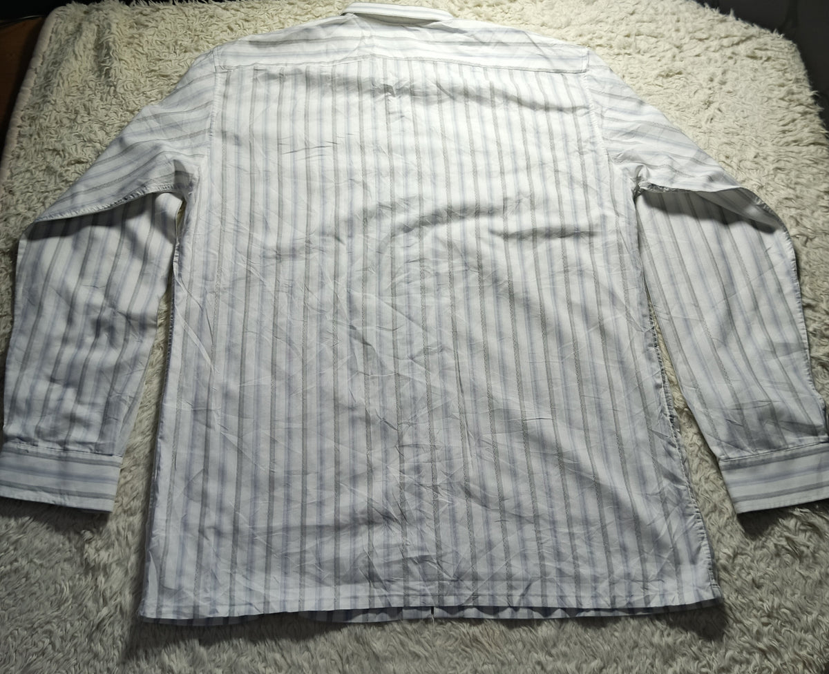 A long-sleeve button-up shirt with vertical light blue and white stripes, laid flat on a textured white shag rug. The photo is taken from above and includes a camera settings overlay at the bottom.