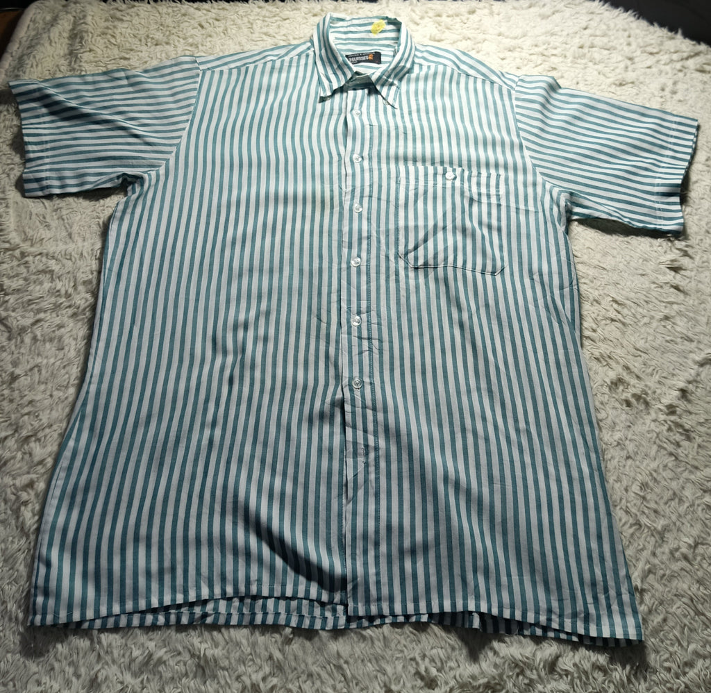 A short-sleeve button-up shirt with vertical blue and white stripes, laid flat on a white shag rug.