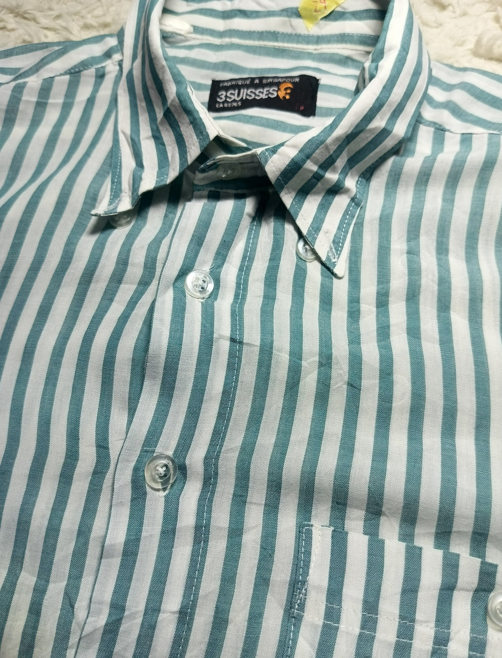 A close-up of a striped button-down shirt with vertical teal and white stripes, featuring a pointed collar, button front, and a visible 3SWISS brand label.