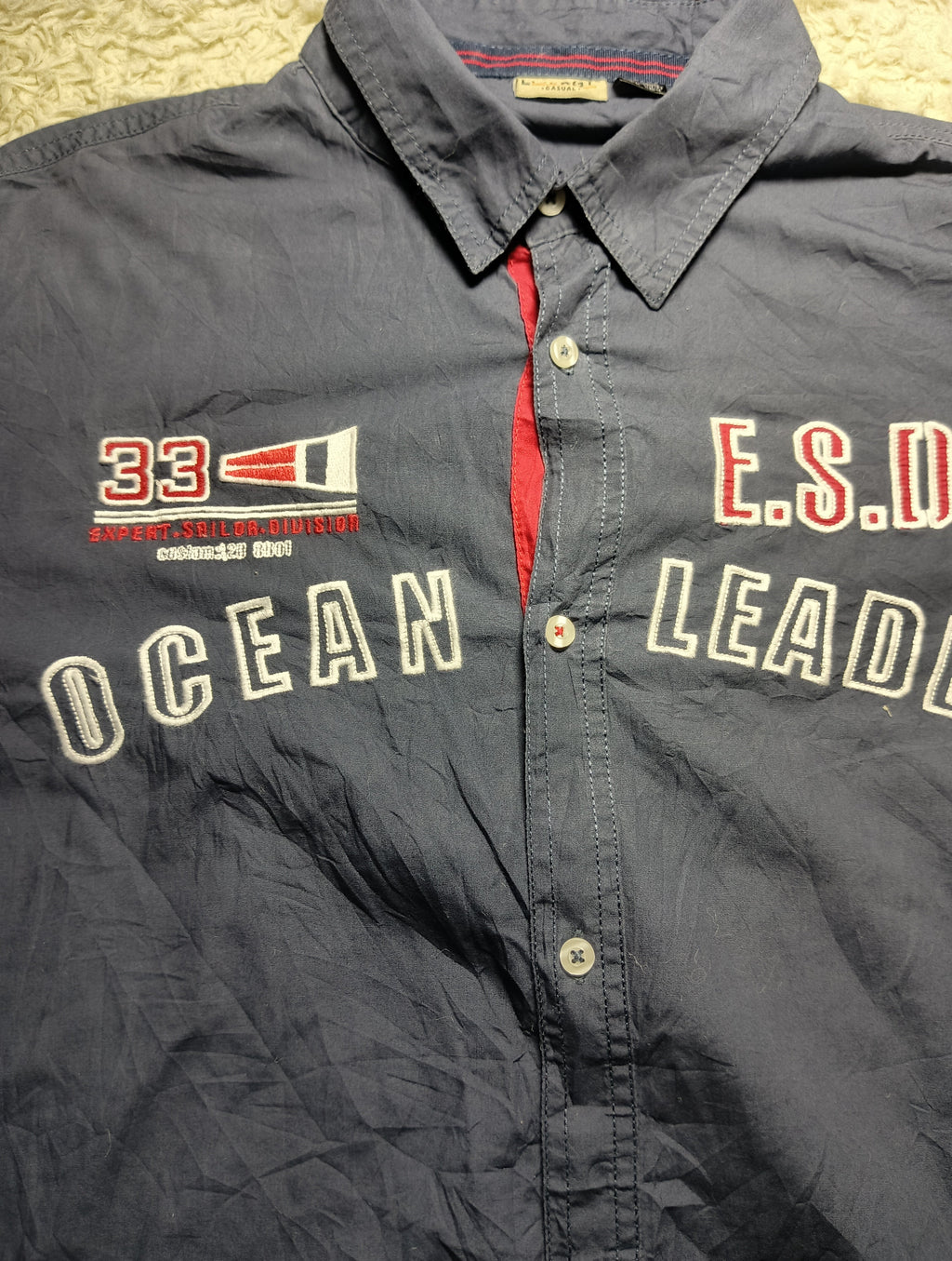 A dark gray button-up shirt with 'OCEAN LEADER' and 'E.S.