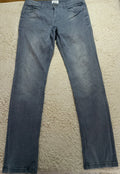 A pair of light blue denim jeans laid flat on a white textured rug, showing a faded wash and standard five-pocket styling.