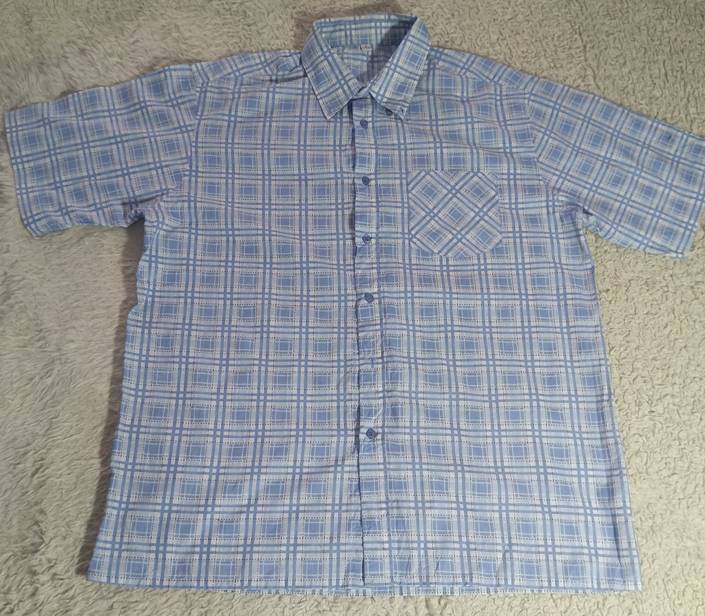A short-sleeve button-up shirt with a blue and white grid pattern, laid flat on a beige shag rug.