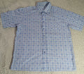 A short-sleeve button-up shirt with a blue and white grid pattern, laid flat on a beige shag rug.