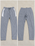 A pair of heather gray sweatpants shown from both front and back views on a textured beige background. The front view shows white side panels and a drawstring waist, while the back view shows a straight, relaxed fit.