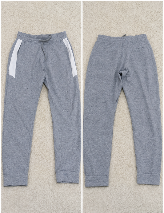 A pair of heather gray sweatpants shown from both front and back views on a textured beige background. The front view shows white side panels and a drawstring waist, while the back view shows a straight, relaxed fit.