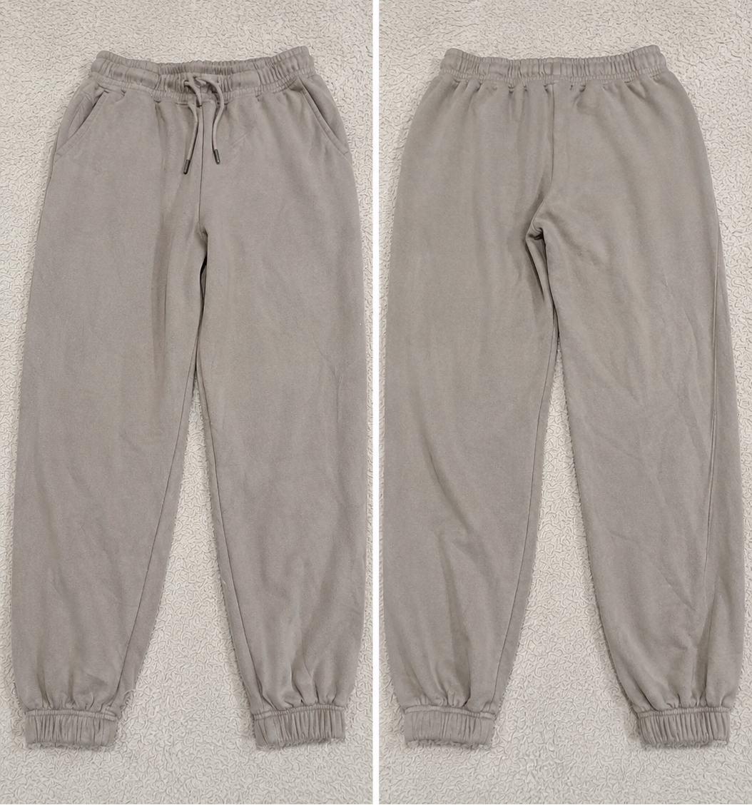 A pair of jogger-style pants shown in a side-by-side split view, labeled 'POVA 6 Neo' with size and color text below each view. The pants are a light warm gray or taupe tone with an elastic waistband, drawstring, side pockets, and elastic cuffs.