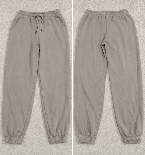 A pair of jogger-style pants shown in a side-by-side split view, labeled 'POVA 6 Neo' with size and color text below each view. The pants are a light warm gray or taupe tone with an elastic waistband, drawstring, side pockets, and elastic cuffs.